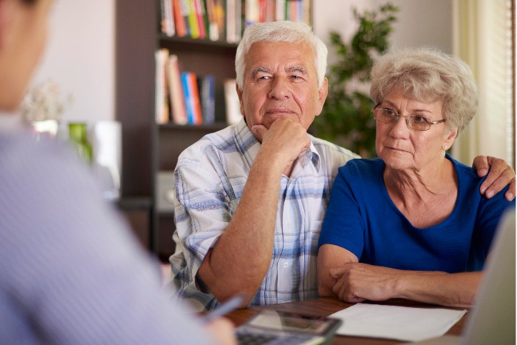 Elderly couple sitting at a table, consulting with The Medicare Broker for Medicare advice.