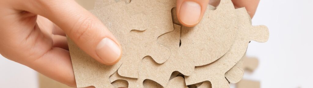 lose-up of hands holding beige puzzle pieces