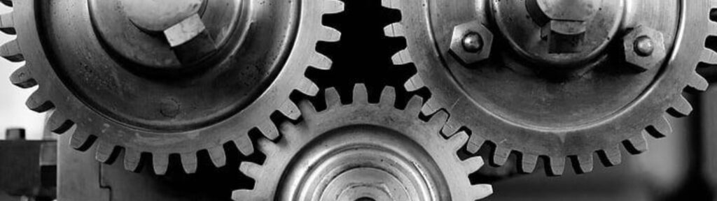 Close-up of interlocking mechanical gray gears with black and white backdrop