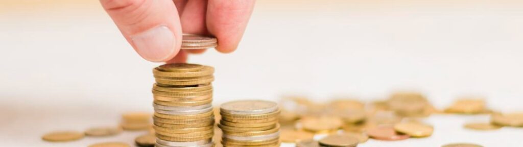 Hand stacking coins to illustrate savings and financial planning for Medicare.